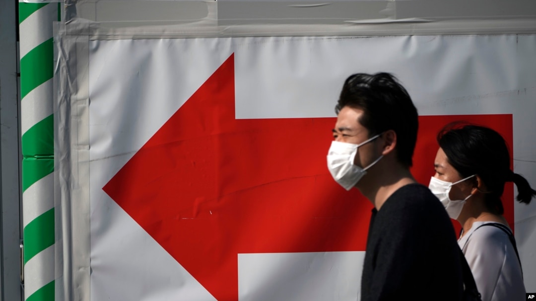 A man and a woman walks near a train station in Tokyo Thursday, April 30, 2020. Japan's Prime Minister Shinzo Abe expanded a state of emergency to all of Japan from just Tokyo and other urban areas as the virus continues to spread. (AP Photo/Eugene…