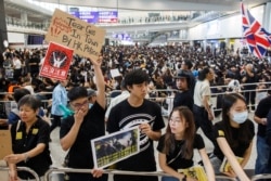 Anti-extradition bill protesters hold up placards for arriving travelers during a protest at the Hong Kong International Airport in Hong Kong, Aug. 9, 2019.