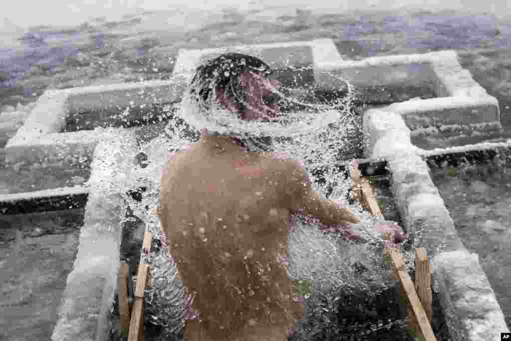 An Orthodox believer bathes in the icy water on Epiphany at a hole in Dnipro river in Kyiv, Ukraine.