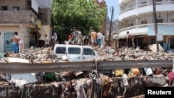 FILE - People inspect damage caused by flooding on a street in Aden, Yemen, April 22, 2020.