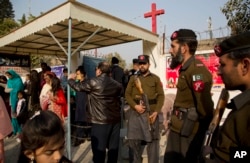 FILE - Pakistani paramilitary officers and policemen are on alert as Pakistani Christians leave a church after Christmas Mass in Islamabad, Dec. 25, 2016. Pakistani Christians frequently complain of being harassed by radicals and at times forced to convert to Islam.