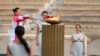 La campeona griega de esquí Paraskevi Ladopoulou (izquierda) enciende la antorcha durante la ceremonia de entrega de la llama olímpica, en el estadio Panathinean, en Atenas, Grecia, el 19 de octubre de 2021.