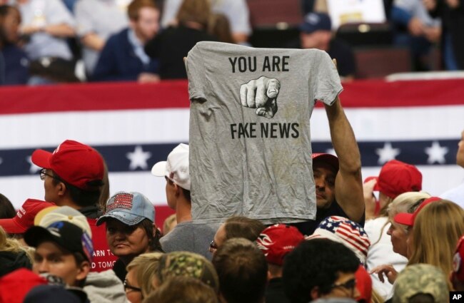 FILE - In this Oct. 4, 2018 file photo, a Trump supporter holds up a T-shirt reading "You Are Fake News" before a rally by President Donald Trump in Rochester, Minn. The Native American Journalists Association worries such rhetoric could impact free speech.