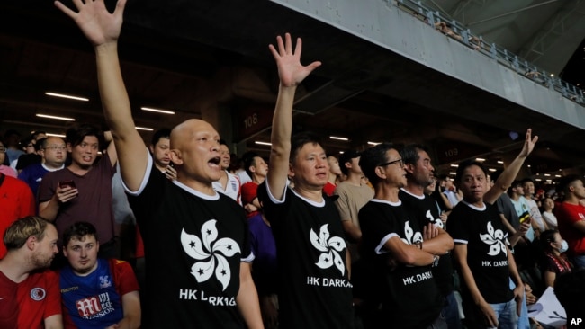 在香港举行的2022年卡塔尔世界杯和2023年亚足联亚洲杯预选赛第二轮香港对阵伊朗的比赛中，香港球迷身穿印有香港国旗黑色图案的T恤抗议政府。(2019年9月10日)
