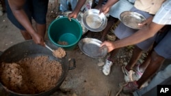 FILE - Students hold out their plates as the school cook ladles out a bulgur wheat and bean dish at a public school in Bombardopolis, Haiti. The WFP says 3.6 million Haitians face food insecurity.