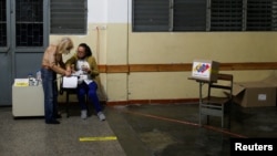 Trabajadores electorales esperan el cierre de la mesa electoral durante la elección de gobernadores estatales y alcaldes, en Caracas, 21 de noviembre de 2021.