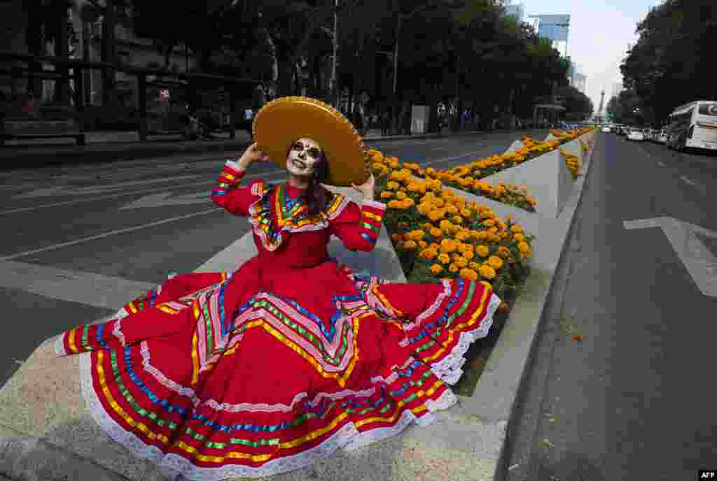 A woman dressed as the character of La Catrina poses before taking part in the Catrinas Parade, commemorating the Day of the Dead, in Mexico City, Oct. 23, 2022.