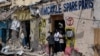 FILE - People stand at the entrance of a destroyed building after a deadly siege by al-Shabab militants in Mogadishu, Somalia, Aug. 21, 2022.