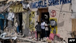 Sejumlah warga berdiri di depan pintu bangunan yang rusak setelah serangan mematikan oleh militan Al-Shabab di Mogadishu, Somalia, 21 Agustus 2022.. (Foto: Hassan Ali Elmi/AFP)