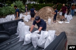 A volunteer loads sand bags into pick up truck for a customer in preparation for the arrival of Hurricane Ian in Tampa, Florida on September 27, 2022. (Photo by Ricardo ARDUENGO / AFP)