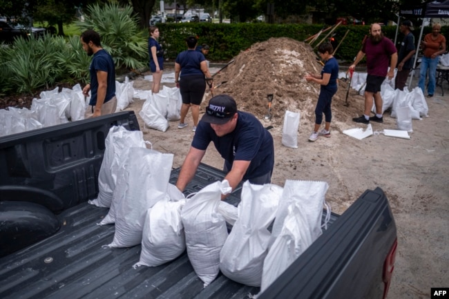 A volunteer loads sand bags into pick up truck for a customer in preparation for the arrival of Hurricane Ian in Tampa, Florida on September 27, 2022. (Photo by Ricardo ARDUENGO / AFP)