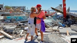 Local muralist Candy Miller, left, embraces Ana Kapel, the manager of the Pier Peddler, a gift shop that sold women's fashions, as she becomes emotional at the site of what used to be the store on the island of Fort Myers Beach, Florida, Sept. 30, 2022.