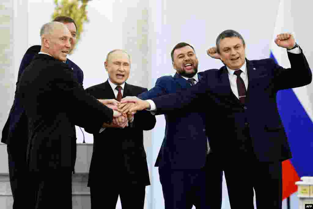 From left to right, the Moscow-appointed heads of Kherson region Vladimir Saldo and Zaporizhzhia region Yevgeny Balitsky, Russian President Vladimir Putin, Donetsk separatist leader Denis Pushilin and Lugansk separatist leader Leonid Pasechnik join hands after signing treaties formally annexing four regions of Ukraine occupied by Russian troops, at the Kremlin in Moscow.&nbsp;