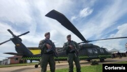 Dos agentes junto a los helicópteros Black Hawk remodelados para la protección del medio ambiente, el 26 de octubre de 2022, en la base de antinarcóticos de la Policía de Colombia, en San José del Guaviare. 