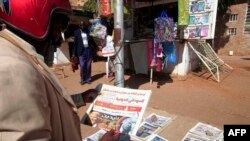FILE - A man reads newspaper headlines in Sudan's capital, Khartoum, Nov. 8, 2020. 