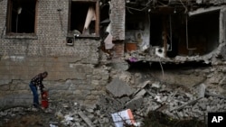 A resident works to clean the debris from damaged house after an overnight Russian shelling in Konstantinovka, eastern Ukraine, Oct. 14, 2022. 