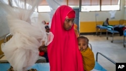 FILE - A woman holds a child at a clinic in Dollow, Somalia, on Wednesday, Sept. 21, 2022. 