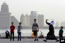 A woman plays badminton by the sea in front of the city skyline in Doha, Qatar, Friday, May 4, 2018. Qatar's residents squeezed as World Cup rental demand soars.(AP Photo/Kamran Jebreili, File)