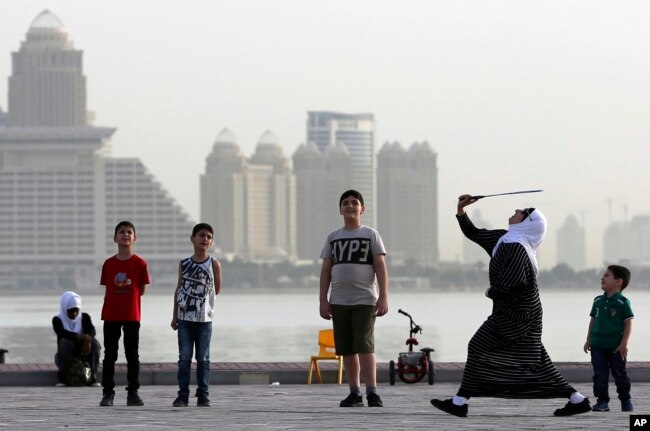 A woman plays badminton by the sea in front of the city skyline in Doha, Qatar, Friday, May 4, 2018. Qatar's residents squeezed as World Cup rental demand soars.(AP Photo/Kamran Jebreili, File)