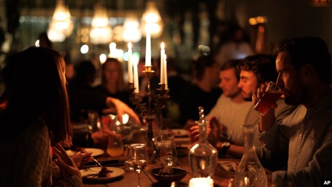 A group of diners have a drink and candle lit dinner at Brasserie Surrealiste in Brussels, Sept. 28, 2022.