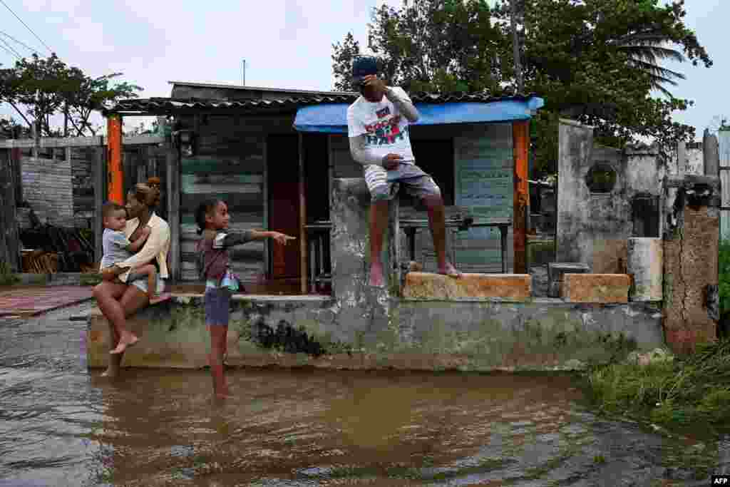 Una familia afuera de su casa inundada en Batabanó, Cuba, el 27 de septiembre de 2022, durante el paso del huracán Ian. (Foto de YAMIL LAGE / AFP)