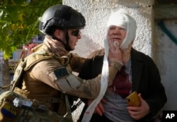 An injured woman receives medical treatment at the scene of Russian shelling, in Kyiv, Ukraine, Oct. 10, 2022.