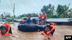 rescue workers evacuating people from a flooded area due to heavy rain brought by Tropical Storm Nalgae in Parang, Maguindanao province. (AFP Photo/Philippine Coast Guard)