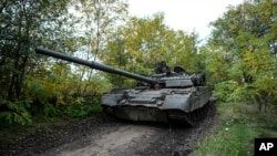 Ukrainian servicemen drive a T-80 tank that they said had been captured from the Russian army, in Bakhmut, Ukraine, Oct. 2, 2022. 