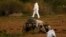 FILE - Forensic experts walk in a field after a bomb blew up a car and killed investigative journalist Daphne Caruana Galizia, in Bidnija, Malta, Oct. 16, 2017.