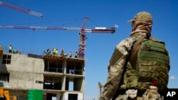 FILE - A Russian soldier guards the site of a new apartment building which is is being built with the support of the Russian Defense Ministry, in Mariupol, on territory under the Government of the Donetsk People's Republic control, eastern Ukraine, on July 13, 2022.