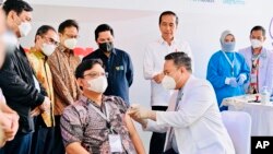 Indonesia President Joko Widodo, center, looks as a medical worker administers a shot of IndoVac COVID-19 vaccine, during the launch of the country's first home-grown COVID-19 vaccine, Indonesia, Thursday, Oct 13, 2022. (Laily Rachev/Indonesian Presidential Palace via AP)