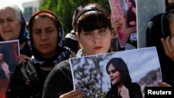 Seorang perempuan memegang poster dalam sebuah protes menyusul kematian Mahsa Amini, di depan markas PBB di Erbil, Irak pada 24 September 2022. (Azad Lashkari/Reuters)