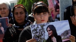 Seorang perempuan memegang poster dalam sebuah protes menyusul kematian Mahsa Amini, di depan markas PBB di Erbil, Irak pada 24 September 2022. (Azad Lashkari/Reuters)