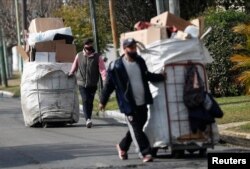 Garbage recyclers push their carts filled with plastic and cardboard as they arrive to the meeting point where they load their carts to a truck carrying it for recycling, in Lomas de Zamora, in the outskirts of Buenos Aires, Argentina July 8, 2022. (REUTERS/Agustin Marcarian)