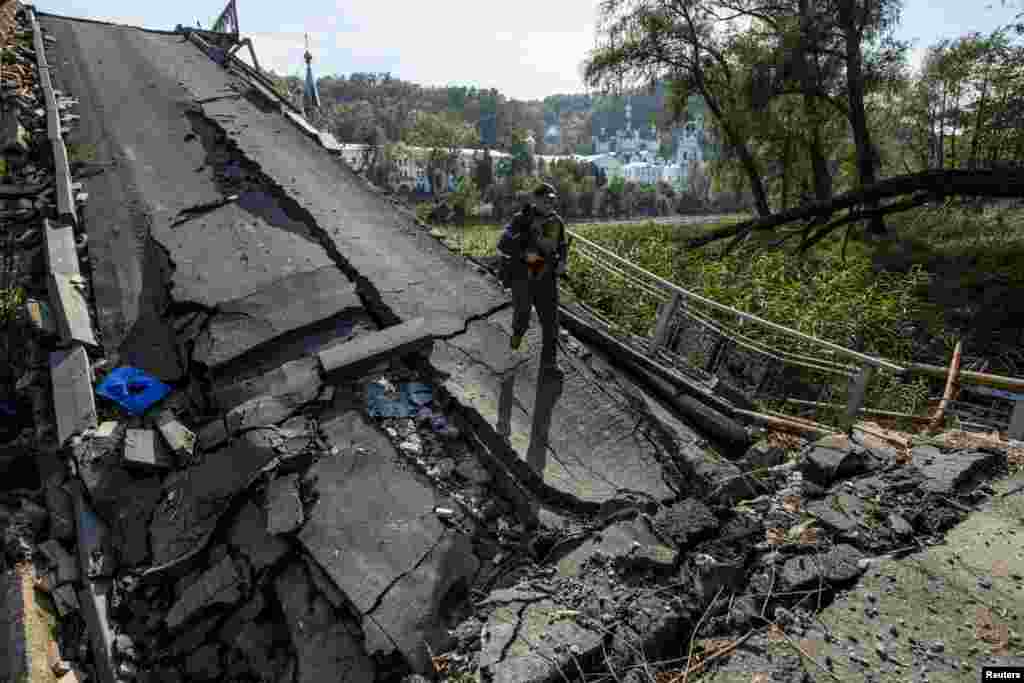A service member of Ukraine&#39;s National Guard walks on a bridge over the Siverskyi Donets river destroyed during Russia&#39;s attack on Ukraine, in the town of Sviatohirsk, Donetsk region, Oct. 1, 2022.