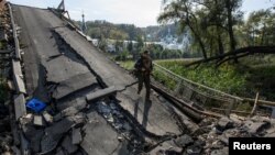 Un miembro del servicio de la Guardia Nacional de Ucrania camina sobre un puente sobre el río Siverskyi Donets destruido durante el ataque de Rusia a Ucrania, en la ciudad de Sviatohirsk, región de Donetsk, Ucrania, el 1 de octubre de 2022.