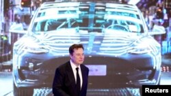 FILE - Tesla Inc CEO Elon Musk walks next to a screen showing an image of Tesla Model 3 car during an opening ceremony for Tesla China-made Model Y program in Shanghai, China, Jan. 7, 2020.