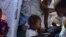 Yon timoun manje sereyal sou plas Hugo Chavez la nan Potoprens, kote anpil fanmi ki kouri pou zak vyolans gang yo ap viv kounyea, 20 Oktob, 2022. 