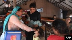 A health worker administers polio vaccine drops to a child during a vaccination campaign in Lahore, Pakistan, October 24, 2022. 