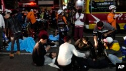 Para petugas SAR dan damkar menolong korban cedera akibat berdesakan di lokasi pesta Halloween in Seoul, Korea Selatan, Minggu, 30 Oktober 2022. Setidaknya 149 orang tewas dan 79 lainnya cedera dalam insiden itu. (Foto: Lee Jin-man/AP) 