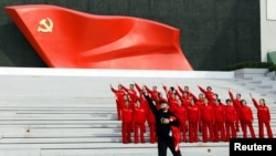 Para pengunjung berpose di depan pemasangan bendera Partai Komunis China, di Museum Partai Komunis China di Beijing, China, 13 Oktober 2022. (Foto: Reuters)