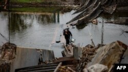 Un hombre lleva botellas de agua mientras cruza un puente destruido en la ciudad de primera línea de Bakhmut, en la región de Donetsk, en el este de Ucrania, el 27 de octubre de 2022, en medio de la invasión rusa de Ucrania.