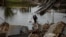 A man carries water bottles as he crosses a destroyed bridge in the frontline town of Bakhmut, in eastern Ukraine's Donetsk region, on Oct. 27, 2022, amid Russia's invasion of Ukraine.