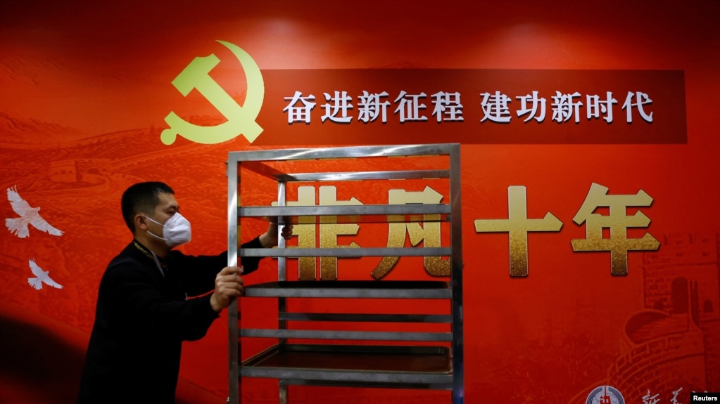 一名工作人员在北京一家酒店的中共二十大新闻中心走过宣传中国领导人习近平的标语。（2022年10月19日）(photo:VOA)