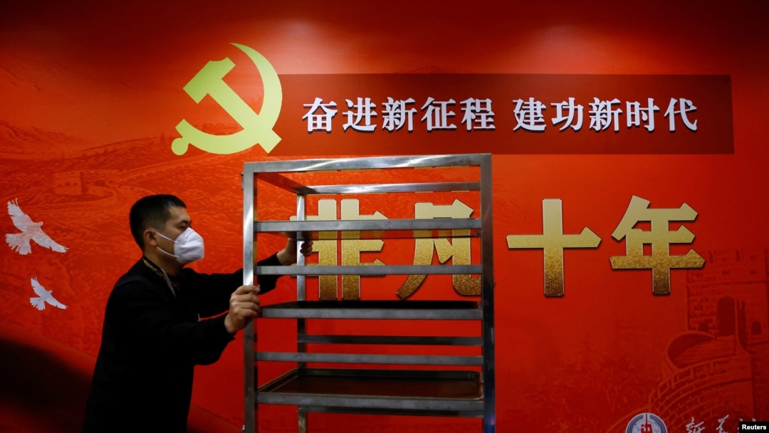 Seorang staf berjalan melewati spanduk mengenai pameran foto 10 tahun pemerintahan Presiden China Xi Jinping, di tengah Kongres Nasional Partai Komunis China ke-20, di Beijing, China, 19 Oktober 2022. ( Foto: REUTERS/Tingshu Wang)