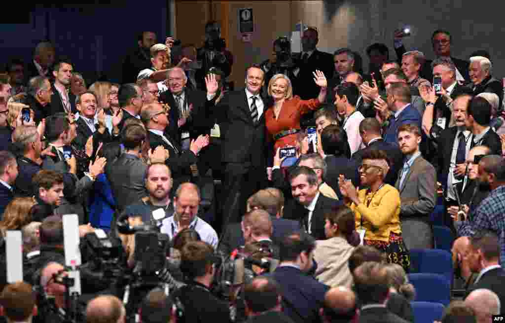 Britain's Prime Minister Liz Truss and her husband Hugh O'Leary wave to applauding delegates after she delivered her keynote address on the final day of the annual Conservative Party Conference in Birmingham, central England.