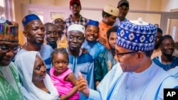 In this photo released by the Nigeria State House, Nigeria's President Muhammadu Buhari, right, meets with freed train hostages in Kaduna Nigeria, Oct. 6, 2022. (Bayo Omoboriowo/Nigeria State House via AP)