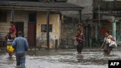 Orang-orang berjalan melalui jalanan yang tergenang banjir setelah dilanda oleh badai Ian di Batabano, Kuba, Selasa 27 September 2022. 