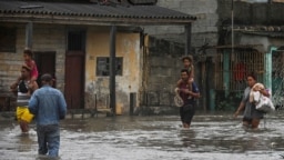 Orang-orang berjalan melalui jalanan yang tergenang banjir setelah dilanda oleh badai Ian di Batabano, Kuba, Selasa 27 September 2022. 