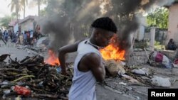 Seorang pria berlari melewati tumpukan barang yang terbakar yang dijadikan barikade dalam aksi protes menentang pemerintah dan kenaikan harga BBM di Port-au-Prince, Haiti, pada 3 Oktober 2022. (Foto: Reuters/Ralph Tedy Erol)